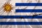 Iron barbed wire on the silk national flag of Uruguay with beautiful folds, the concept of a ban on tourism, political repression