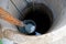 Iron bucket with water at the depth of a round well