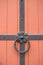 Iron doorknocker on orange wooden door