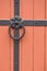 Iron doorknocker on orange wooden door