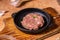 Iron frying pan with raw cutlet on a wooden board