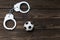 Iron handcuffs for the detention of criminals, a soccer ball on a wooden background.
