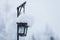 An iron lantern hangs on a pole with a huge cap of snow