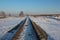 Iron rails the path for the train in the direction of freight covered with snow at the railway crossing in the winter