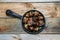 Iron skillet full of roasted chestnuts on a wooden background