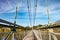 Iron steel frame construction of pedestrian suspension bridge across the river. wide angle view