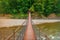 Iron suspension pedestrian bridge over mountain river