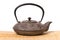 Iron teapot on wooden mat.