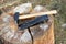 An iron wedge and a hammer are placed on a split wooden log.