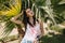 Irresistible girl with dark straight hair resting in shade of palm trees enjoying vacation in exotic country. Portrait