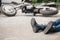 Irresponsible motorcyclist lying on the road and motorbike in th