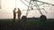 irrigation agriculture. two silhouette farmers working in the field examining installation for irrigating corn in field