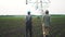 Irrigation agriculture. Two silhouette farmers working in the field examining lifestyle installation for irrigating corn