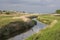 Irrigation ditch, green meadows and pasture