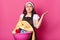 Irritated angry housewife posing isolated over bright pink background, making gesture, raising her hand aside with annoyance,