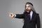 Irritated arabian muslim businessman in keffiyeh kafiya ring igal agal classic black suit isolated on gray background