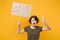 Irritated young protesting girl hold protest sign broadsheet placard on stick, plastic bottle isolated on yellow