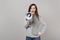 Irritated young woman in gray sweater scarf scream in megaphone isolated on grey background studio portrait. Healthy