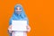 Islamic or muslim woman in hijab wearing mask protect covid-19 virus hiding behind white blank board