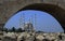 The islamic structure under both the bright blue sky and the stone bridge and it\'s fascinating scenery