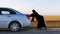 An Islamic woman is pushing a car along the road. Woman driver car breakdown