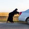 An Islamic woman is pushing car along the road. Woman driver - car breakdown