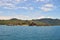 Island covered with tropical vegetation in the South China Sea, coastline, hills, against a blue sky covered with clouds