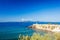 Island of Elba on horizon visible against lighthouse and Piazza Bovio in Piombino, Tuscany
