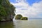 Island, rock in the Atlantic Ocean covered with green vegetation, against a backdrop of the shore in the background. Los Haitises