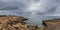 Island scenery with rocks and sea in gloomy weather, lighthouse