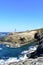 Island with two lighthouses and violet flowers. View from a cliff, sunny day. Isla Pancha, Ribadeo, Spain.