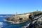 Island with two lighthouses and violet flowers. View from a cliff, sunny day. Isla Pancha, Ribadeo, Spain.