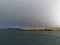 The Isle of Bressay with its Grass and heather covered land lit up by the Winters sun under the dark clouds of a Winters Storm