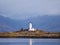 Isle Ornsay with white tower of Lighthouse; Isle of Skye; Scotland. Sunny winter day with snowy mountains