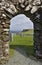 Isle of Skye, Scotland - View through the archway of ruined Trumpan church across a green grassy graveyard towards a distant sea c