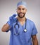 This isnt going to hurt. a handsome young nurse standing alone in the studio and holding a syringe.