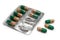 Isolate. Seven green capsules with medicine in a blister pack and three separately on a white background