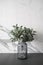 Isolated artificial plant in glass vase on gray spray-painted  working table with  marble wall in the background /apartment interi