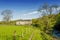 An isolated barn set in green English countyside by a path running alongside a river.