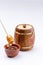 An isolated barrel on a white background. A wooden bowl and honey stick with flowing honey into the cup