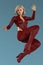 Isolated beautiful urban fantasy woman in red leather bodysuit jumping in the air