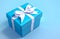 An isolated blue gift box with white ribbon in 3d rendering style on a pastel blue background.