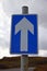 Isolated blue and white one way sign UK with white arrow on blue background