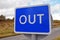 Isolated blue and white rectangular OUT sign with blurred road and rural background