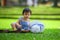 Isolated candid portrait of sweet and adorable Asian Korean baby girl 3 or 4 months old playing with hat alone at city park