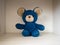 Isolated children`s toy on a light wooden texture background, old torn blue teddy bear from childhood
