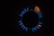 Isolated close up shot of a blue and orange circular fire with small flames on the perimeter coming from a kitchen gas stove and