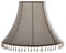 Isolated close up shot of a classic cut corner bell shaped white beige tapered lampshade with a beaded fringe on a white backgrou