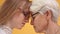 Isolated close up shot of young and senior woman touching foreheads