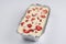 Isolated close up top corner view of a Russian zapekanka strawberry pudding cottage ice cream cheese cake in a foil baking pan on